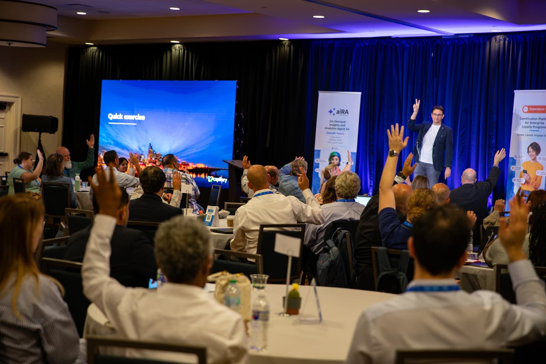 Audience members raising their hands during an exercise led from the stage