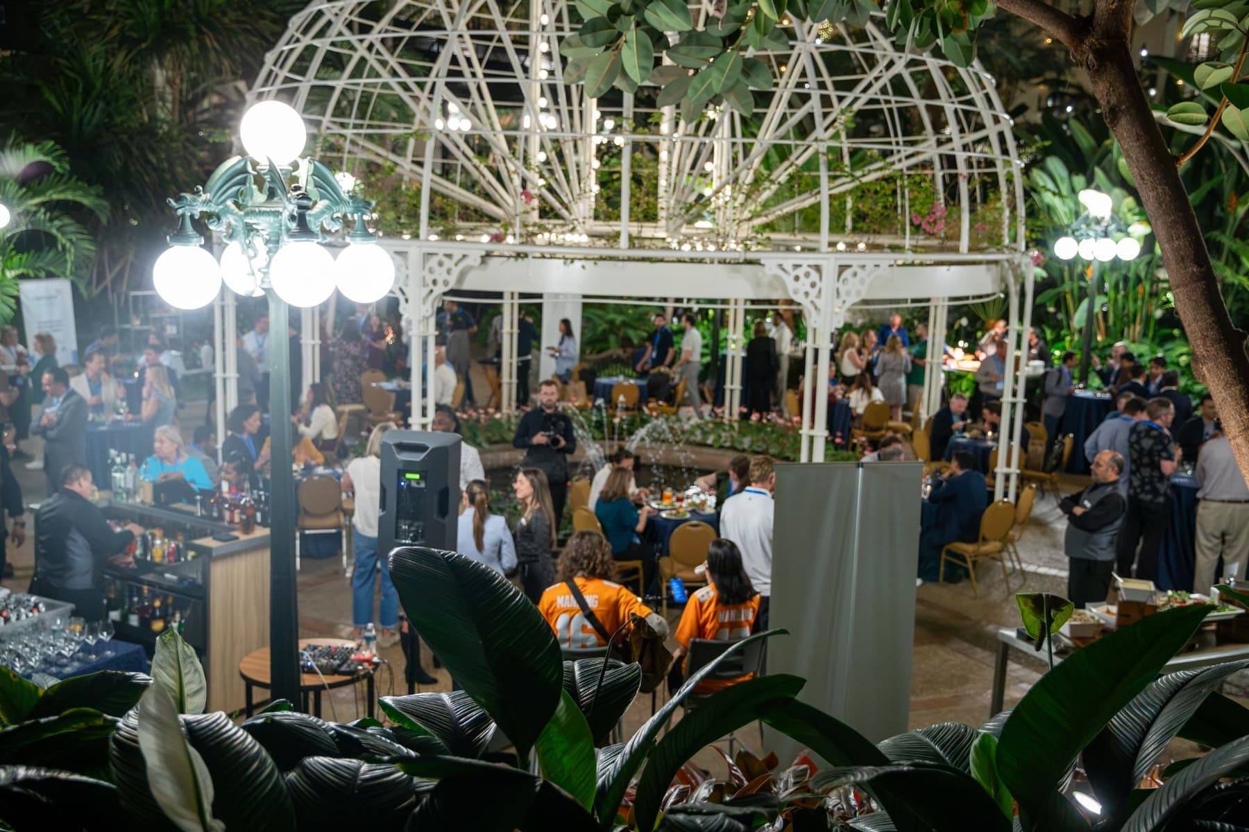 Guests at tables and a bar around a lit gazebo during the evening reception